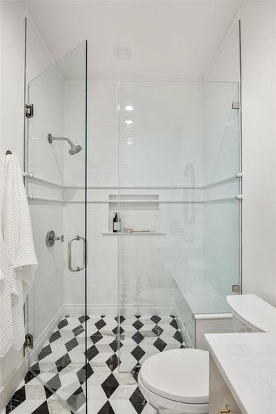 Stunning walk-in shower with continued moscaic tile floor and subway tile surround in shower.