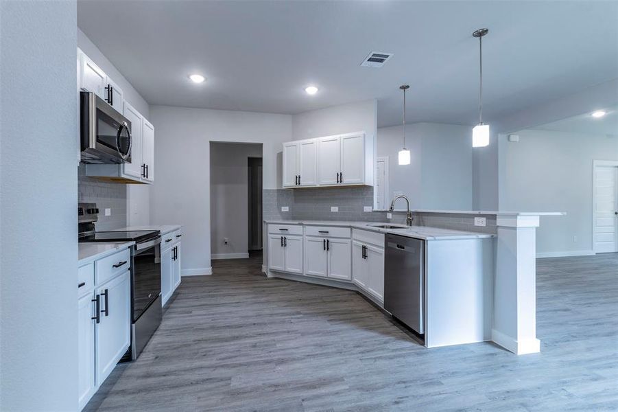 Kitchen featuring light hardwood / wood-style flooring, white cabinets, and appliances with stainless steel finishes