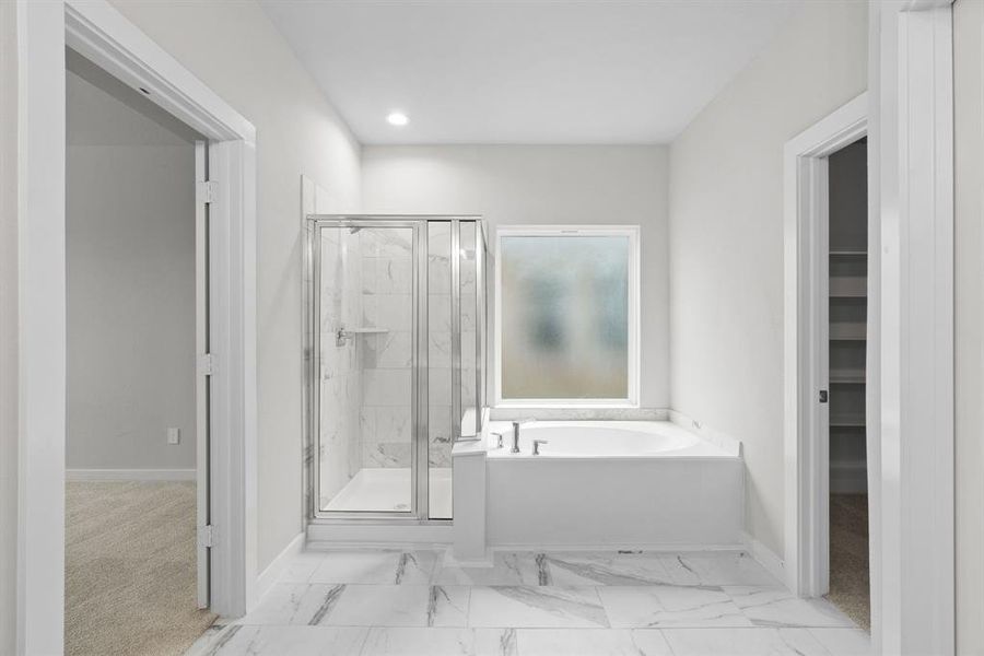 This additional view of the primary bath features a walk-in shower with the tile surround and separate garden tub perfect for soaking after a long day. Sample photo of completed home with similar floor plan. As-built interior colors and selections may vary.