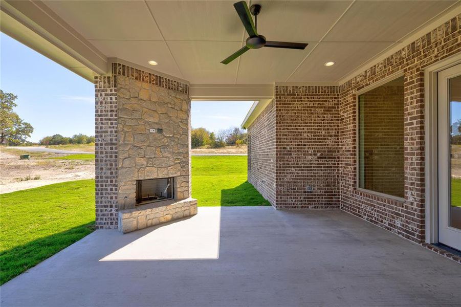 View of patio / terrace with ceiling fan and an outdoor stone fireplace