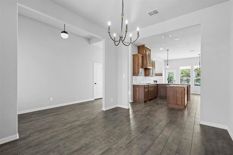 Kitchen featuring dark hardwood / wood-style floors, decorative light fixtures, a notable chandelier, kitchen peninsula, and decorative backsplash