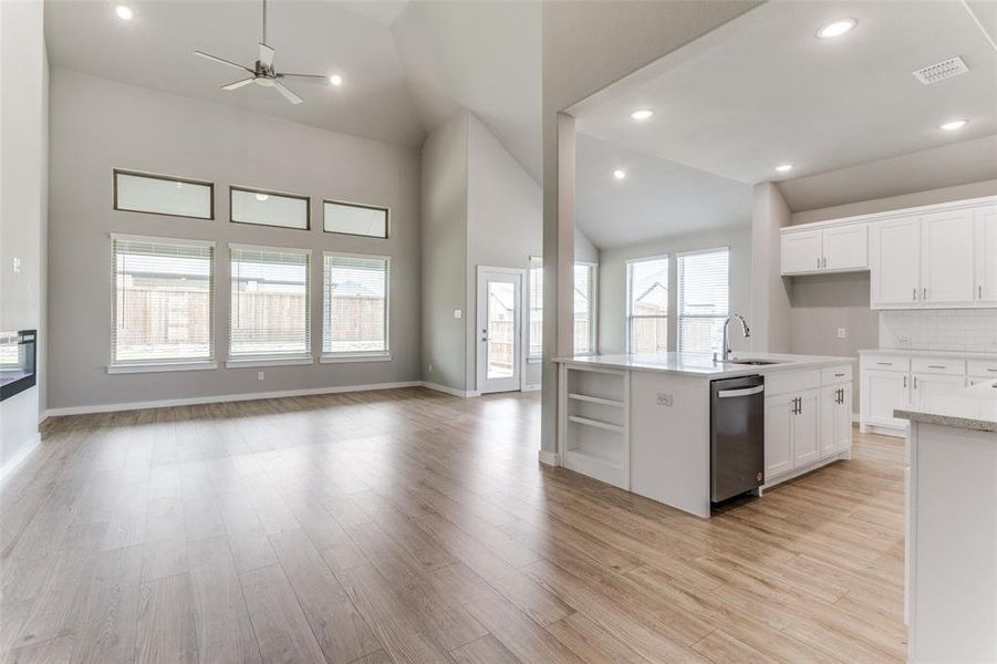 Kitchen with white cabinetry, light hardwood / wood-style flooring, dishwasher, decorative backsplash, and sink