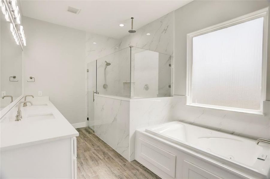 PAMPER YOURSELF IN THIS LUXURIOUS MASTER BATHROOM, COMPLETE WITH A SPACIOUS WALK-IN SHOWER, AND A LARGE SOAKING TUB UNDER A FROSTED WINDOW.