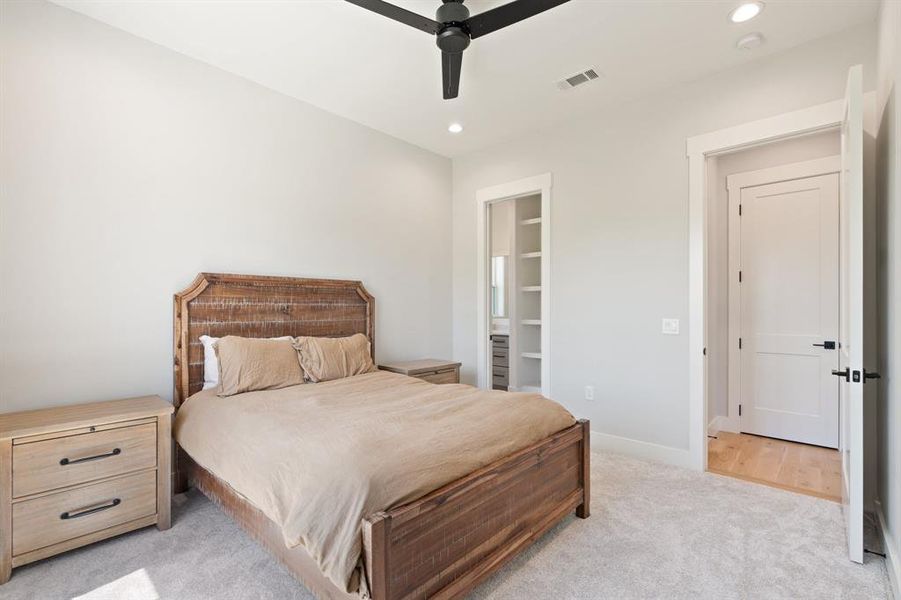 Bedroom featuring ceiling fan, light carpet, and a spacious closet