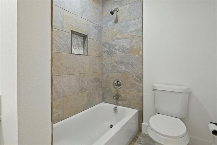 Bathroom with tiled shower / bath and toilet