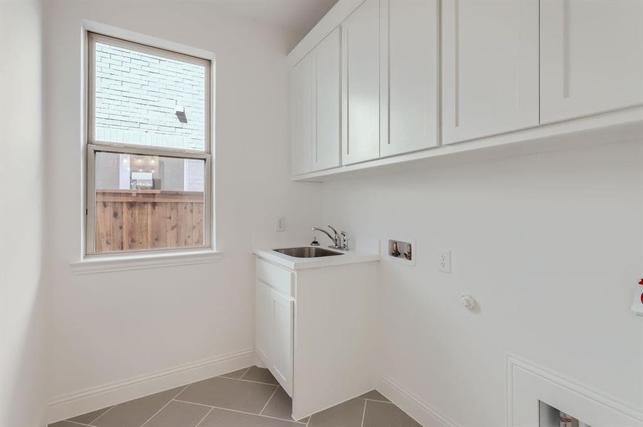 Laundry room with cabinets, hookup for a washing machine, sink, and dark tile patterned floors