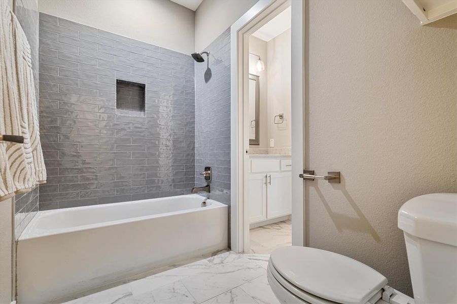 Full bathroom featuring tile patterned flooring, toilet, tiled shower / bath combo, and vanity