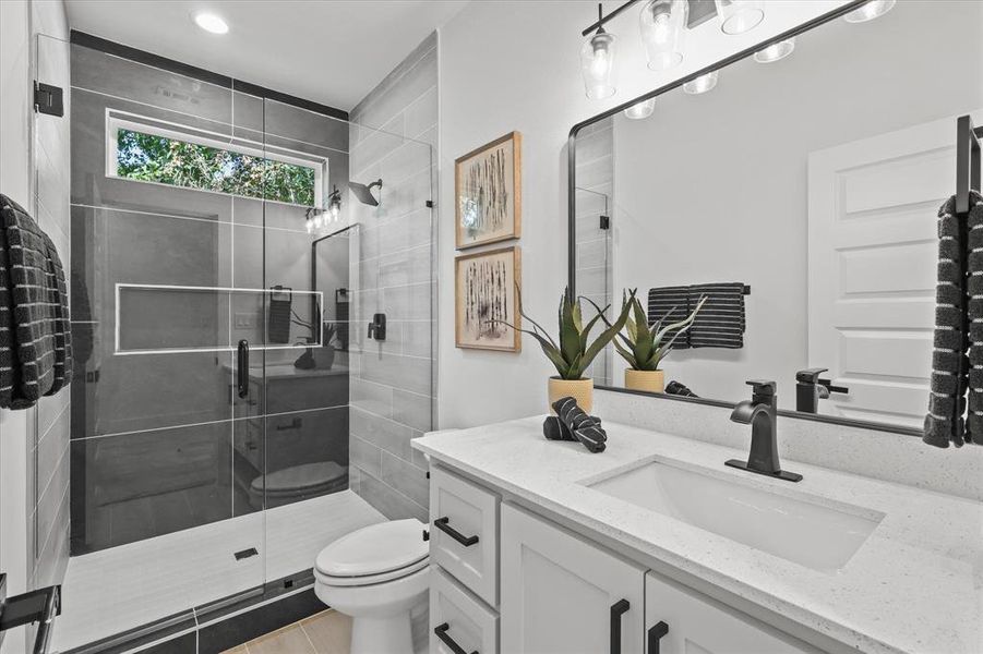 Bathroom with vanity, toilet, a shower with shower door, and tile patterned flooring