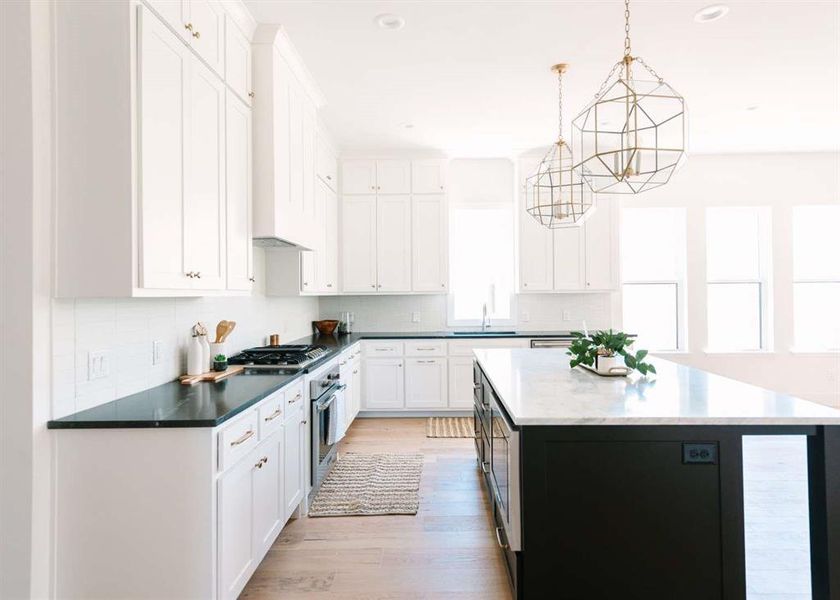 Kitchen featuring appliances with stainless steel finishes, white cabinets, a center island, light hardwood / wood-style flooring, and decorative light fixtures