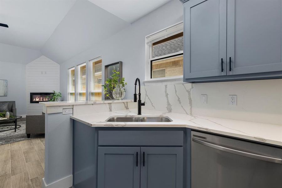 Kitchen featuring a wealth of natural light, lofted ceiling, sink, and stainless steel dishwasher