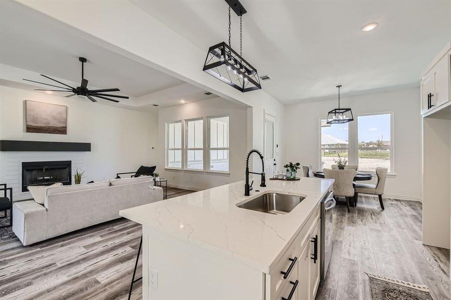 Kitchen with pendant lighting, sink, ceiling fan with notable chandelier, white cabinets, and light stone countertops