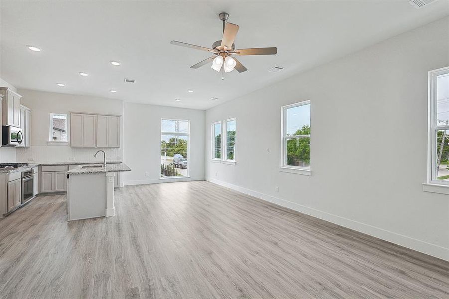 Kitchen featuring plenty of natural light, a kitchen island with sink, light wood-type flooring, and ceiling fan