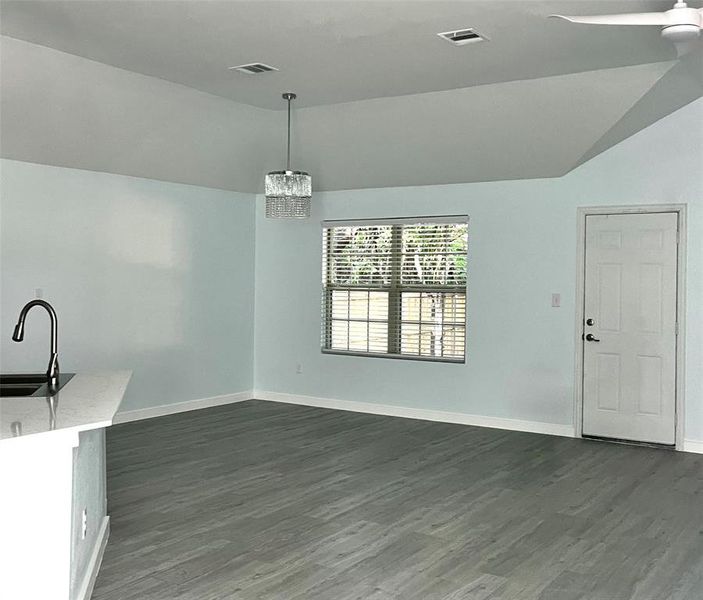 Unfurnished dining area featuring sink, lofted ceiling, and dark hardwood / wood-style floors