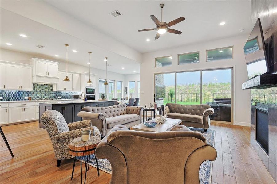 Living room featuring light wood-type flooring, ceiling fan, and a tile fireplace