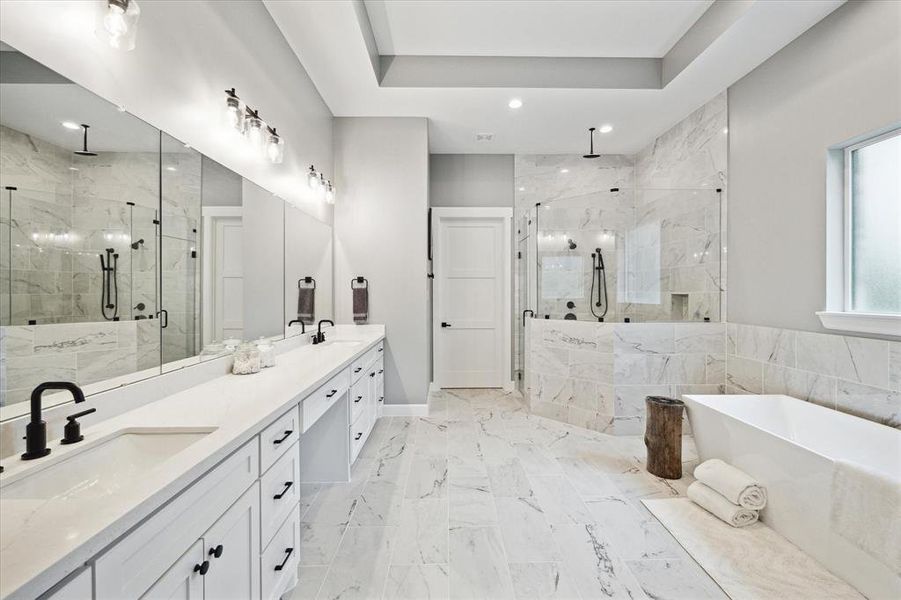Primary bathroom with tile floors, dual sinks, recessed and sconce lighting, and tray ceiling.