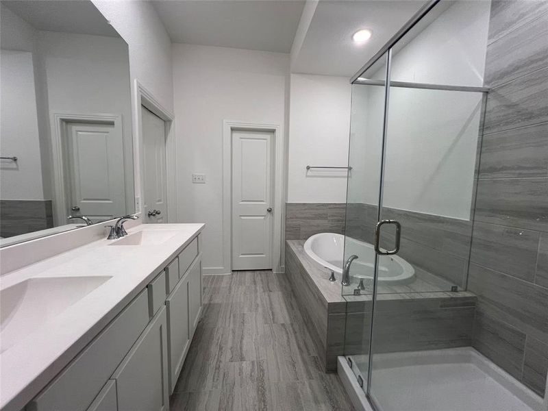 Bathroom featuring dual sinks, vanity with extensive cabinet space, and separate shower and tub