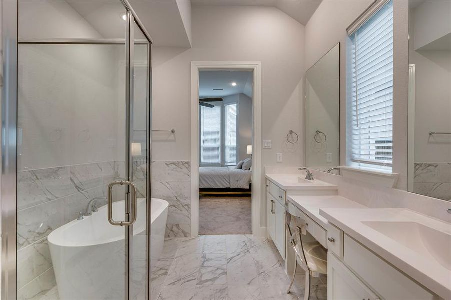Bathroom featuring tile patterned flooring, double sink vanity, tile walls, shower with separate bathtub, and vaulted ceiling
