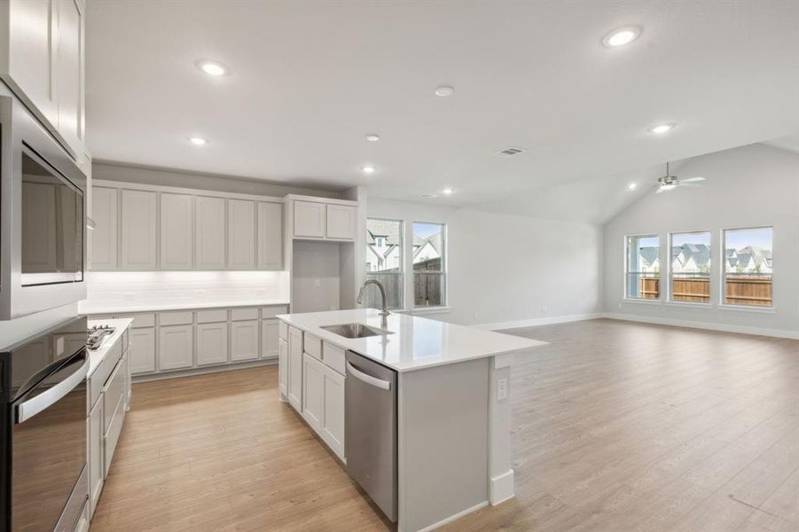 Kitchen with an island with sink, light hardwood / wood-style flooring, ceiling fan, and appliances with stainless steel finishes