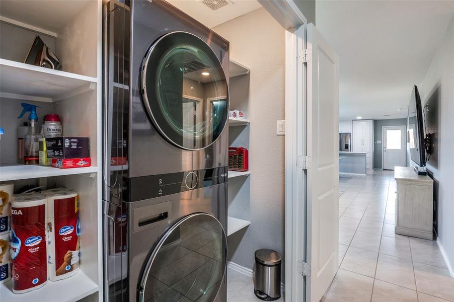 Laundry closet was custom built with shelves and a stacked washer and gas dryer that will remain with the home. This allows for so much extra storage space.