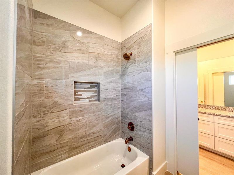 Bathroom featuring tiled shower / bath, vanity, and hardwood / wood-style flooring