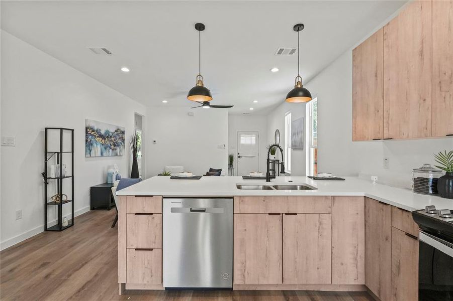 Kitchen with light wood-type flooring, dishwasher, sink, kitchen peninsula, and light brown cabinetry