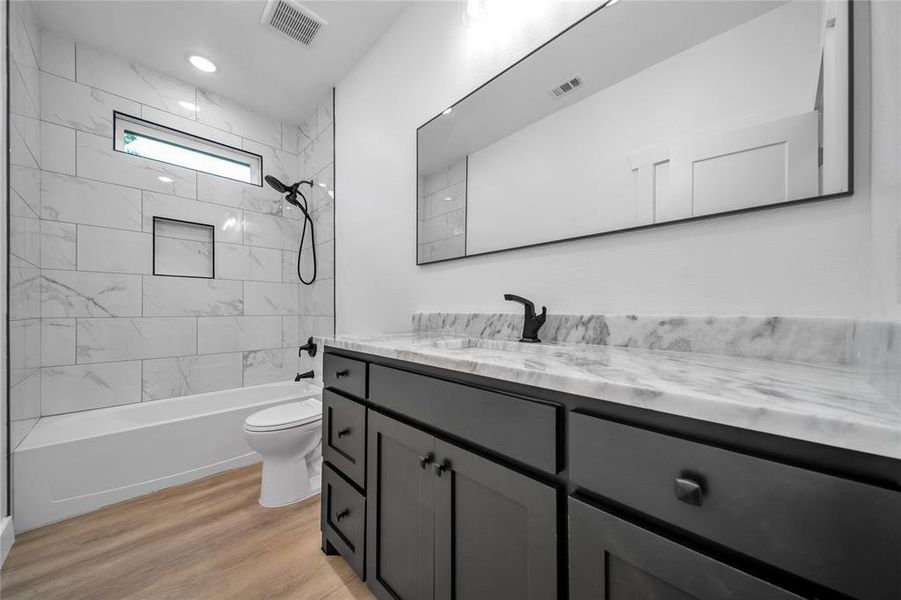 Full bathroom featuring toilet, vanity, wood-type flooring, and tiled shower / bath