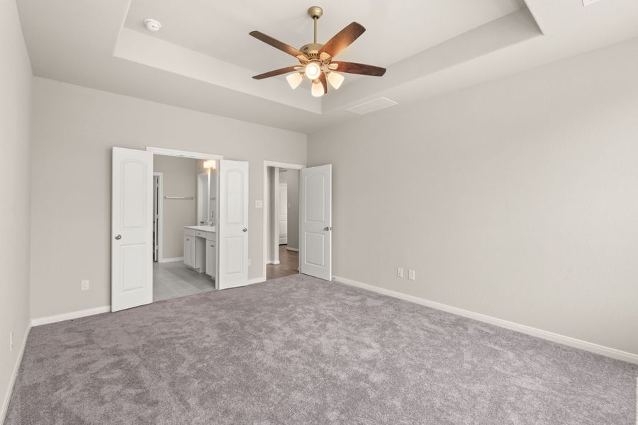 An additional view of the primary bedroom with double doors leading to the en-suite.