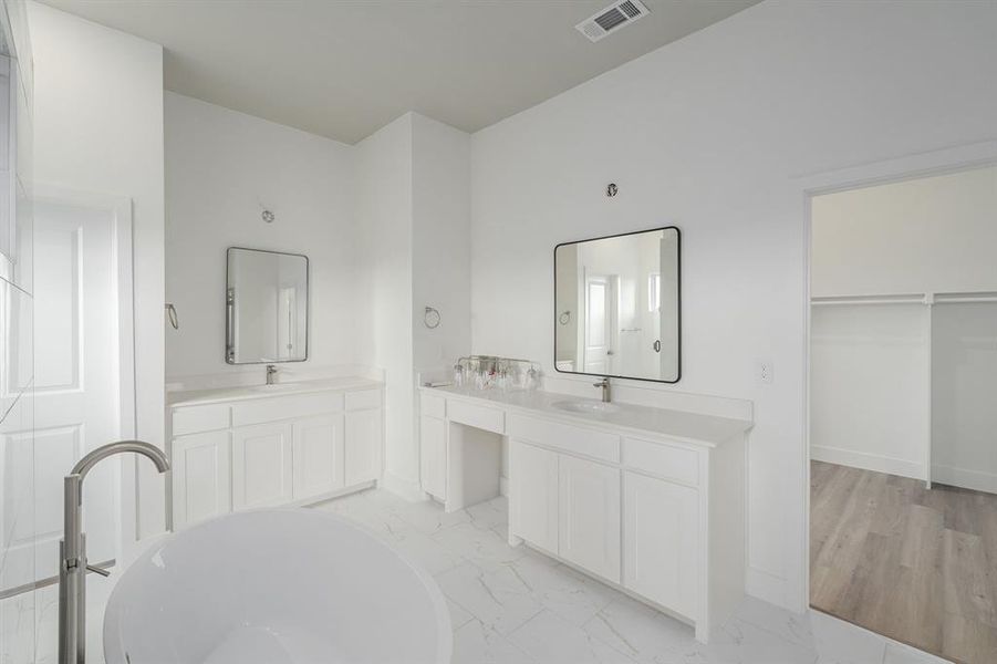 Bathroom featuring vanity, a bath, and wood-type flooring