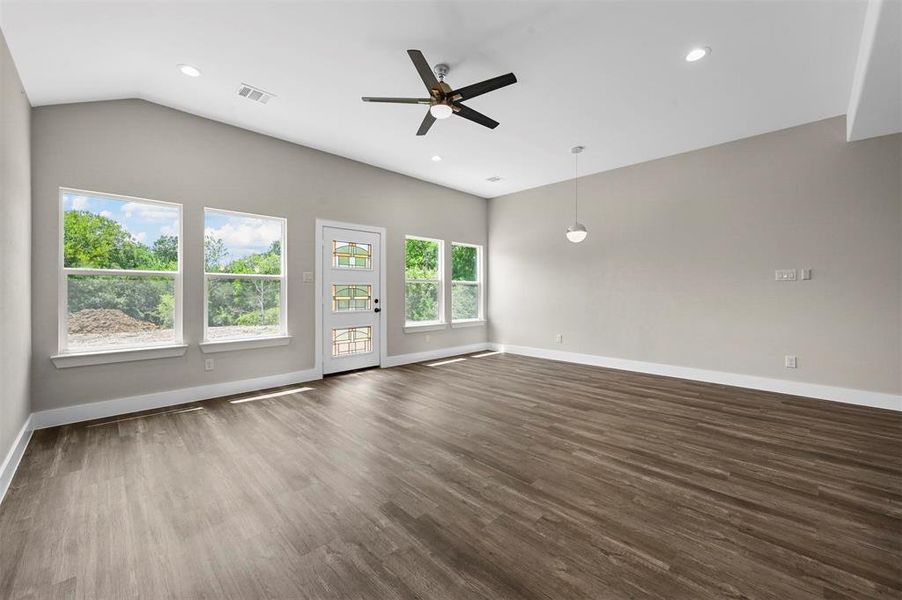 Spare room featuring dark hardwood / wood-style floors, ceiling fan, and vaulted ceiling