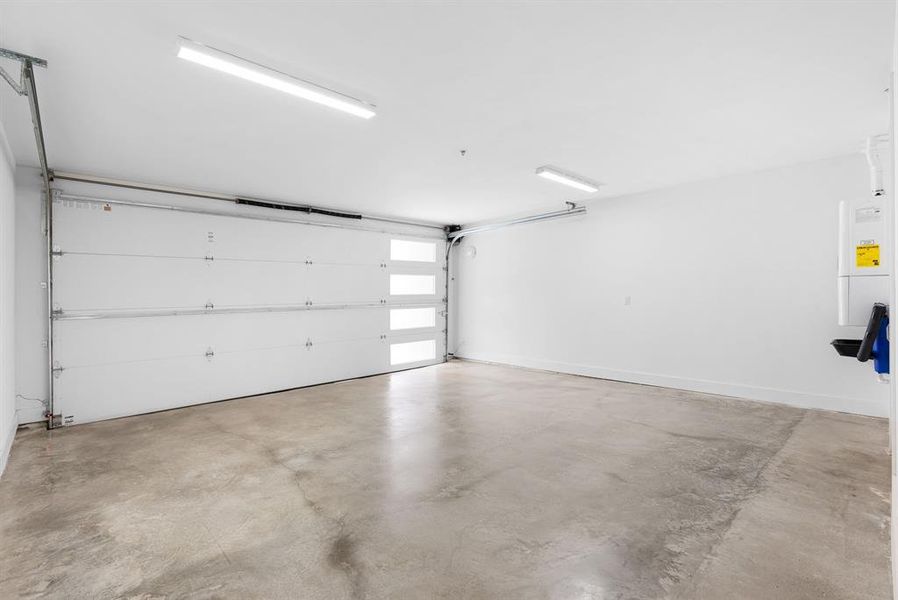 Spacious two car garage with tankless hot water heater, bright overhead lighting, and electric is available for charging stations.