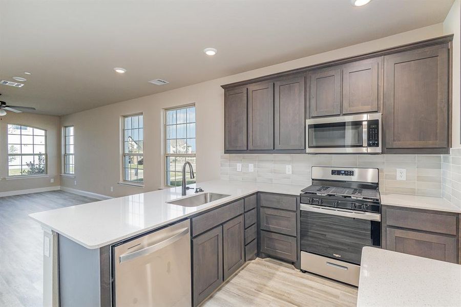 Kitchen featuring sink, kitchen peninsula, stainless steel appliances, and backsplash