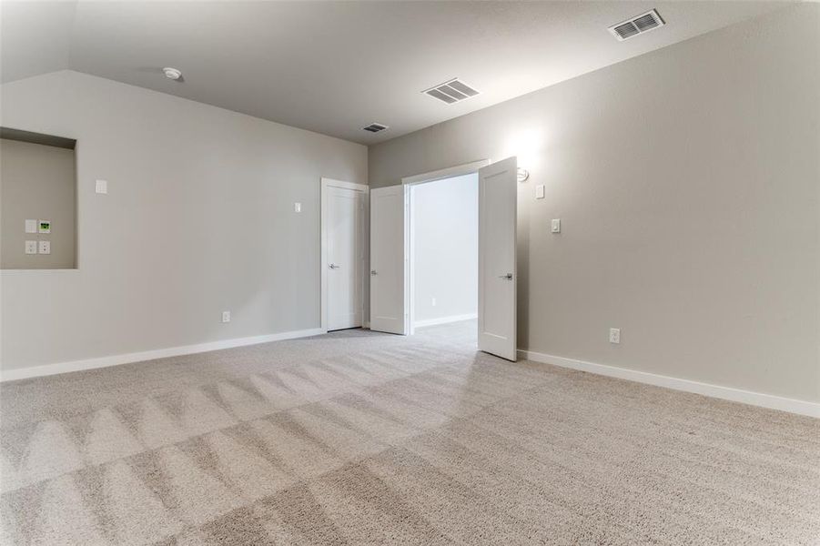 Empty room with light carpet and vaulted ceiling