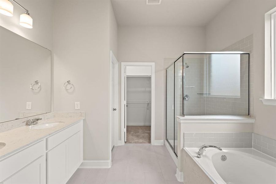 This additional view of your primary bathroom features tile flooring, fresh paint, walk-in shower, a separate garden tub, and a large walk-in closet.