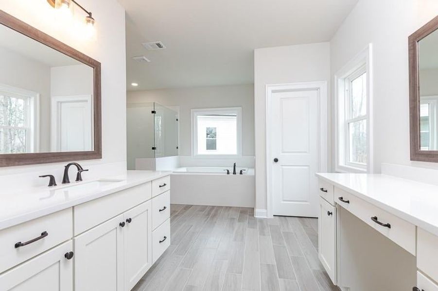 The owner's bath is sure to impress with its fabulous entryway, dual sinks, soaking tub, and walk-in shower   Photo not actual home, but previously built Mansfield plan.