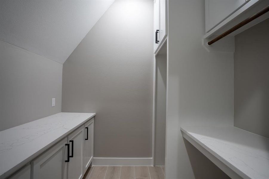 Laundry room has a folding table, hanging rack and is ready for a stackable washer and dryer.