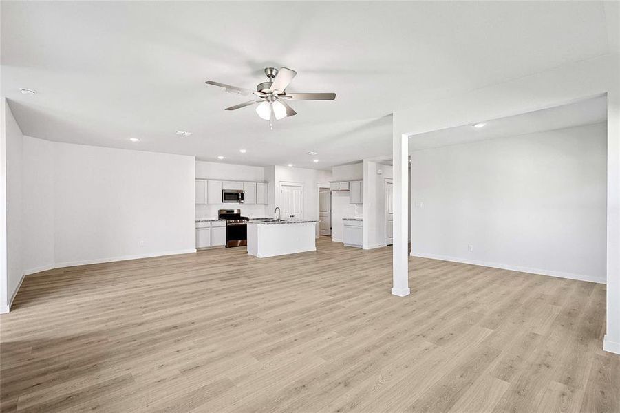 Unfurnished living room featuring sink, light hardwood / wood-style flooring, and ceiling fan