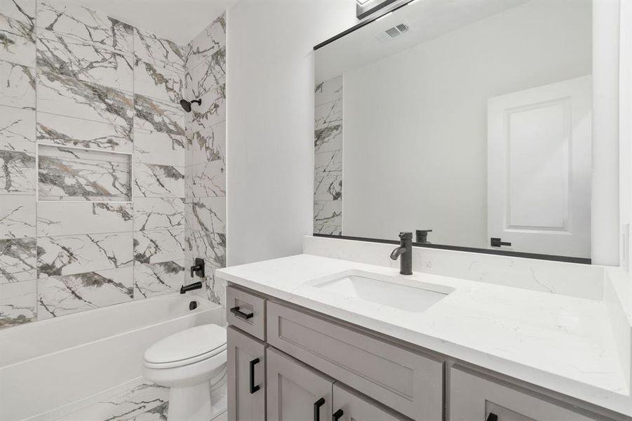 Full bathroom featuring tiled shower / bath combo, vanity, and toilet