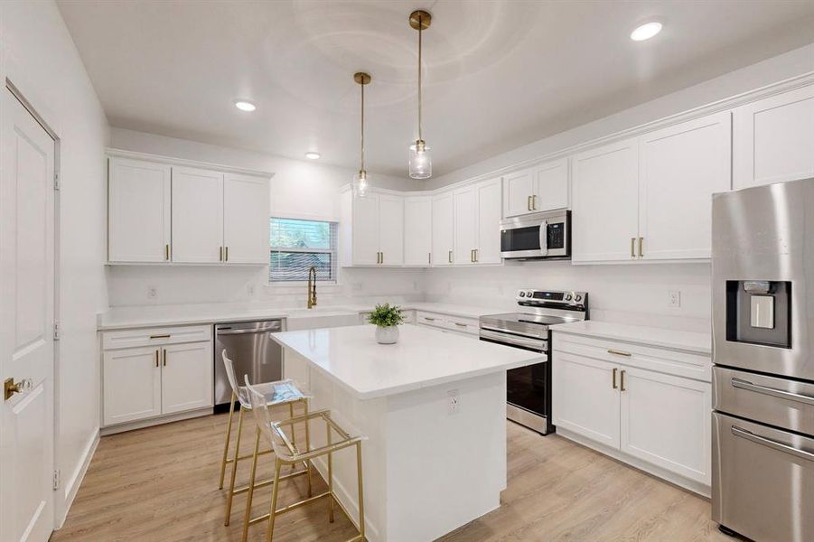 Kitchen with pendant lighting, a center island, white cabinets, and stainless steel appliances