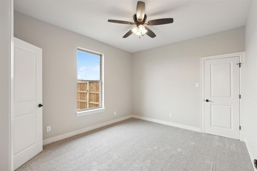 Carpeted empty room featuring ceiling fan