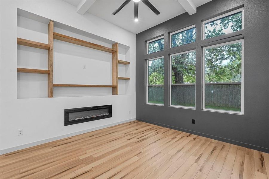 Unfurnished living room with beamed ceiling, ceiling fan, and wood-type flooring