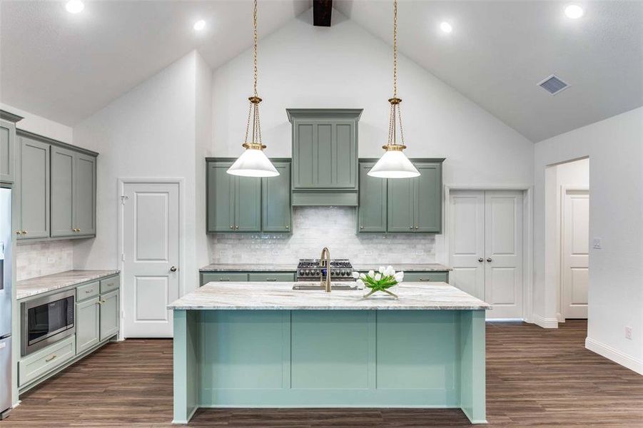 Kitchen with dark wood-type flooring, custom range hood, backsplash, high vaulted ceiling, and appliances with stainless steel finishes