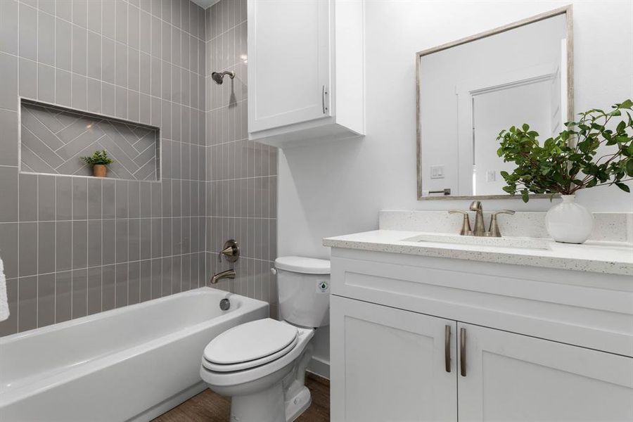 Full bathroom with vanity, toilet, tiled shower / bath combo, and wood-type flooring