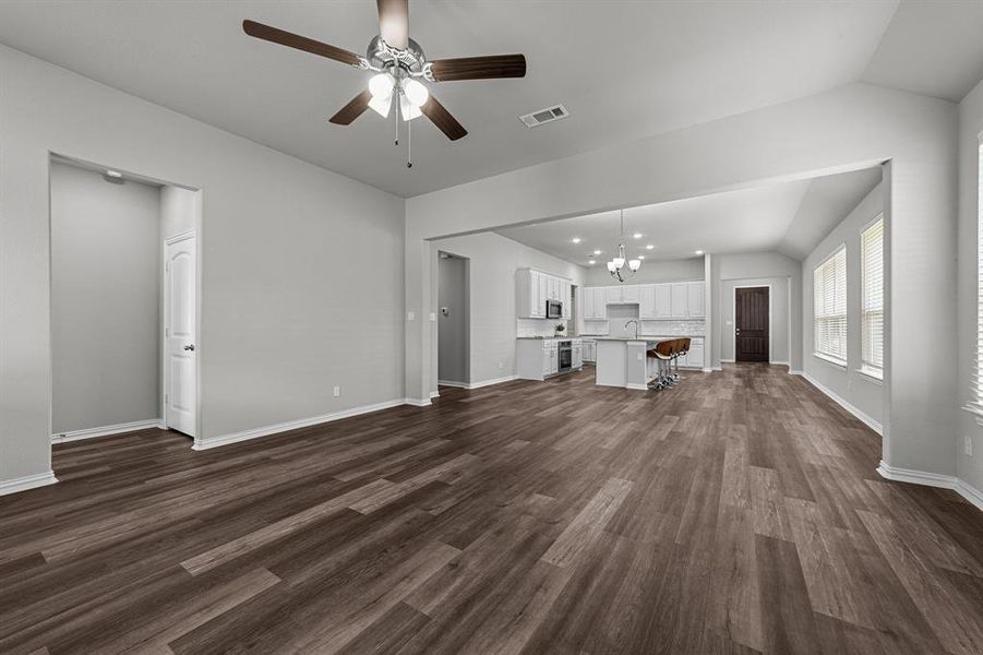 Unfurnished living room with vaulted ceiling, sink, ceiling fan with notable chandelier, and dark hardwood / wood-style flooring