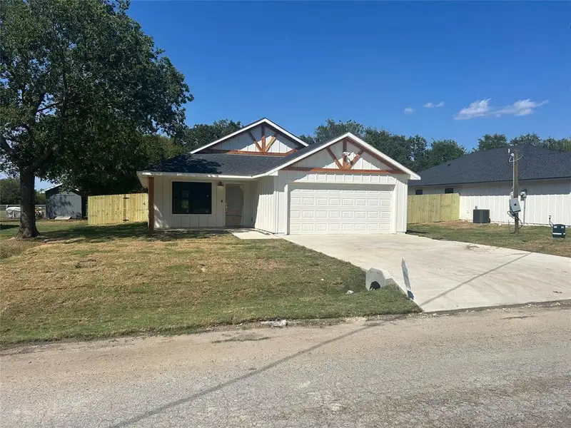 View of front facade featuring a front yard and a garage