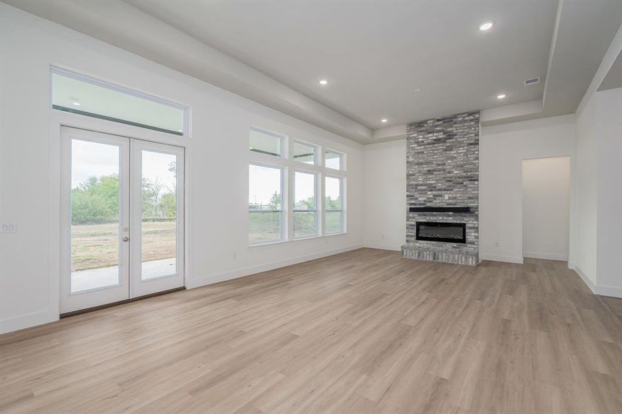 Unfurnished living room featuring a fireplace, french doors, plenty of natural light, and light hardwood / wood-style floors