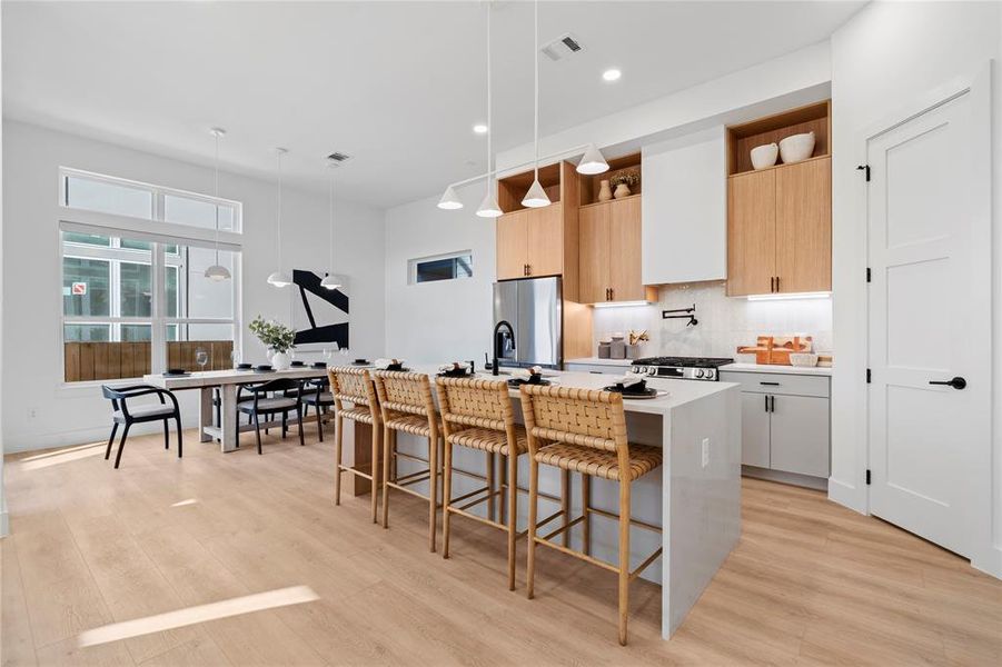 This sleek kitchen and dining area offers seamless flow, with a large island for casual seating, custom cabinetry, and bright natural light. The open layout is perfect for both entertaining and everyday living, blending style with function effortlessly.