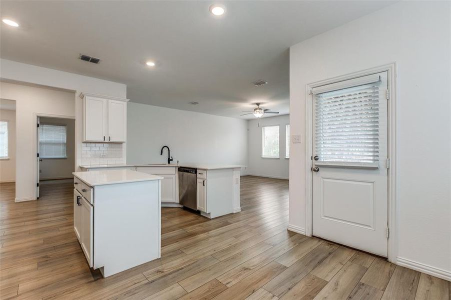 Kitchen featuring white cabinetry, kitchen peninsula, light hardwood / wood-style flooring, and stainless steel dishwasher