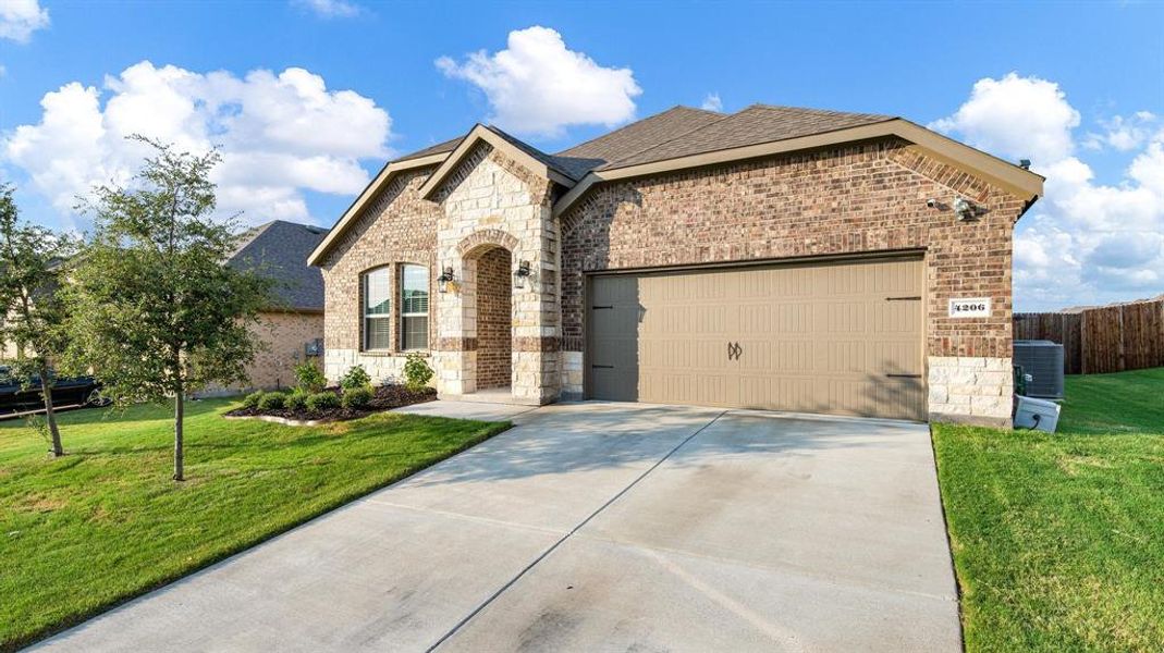 View of front of home featuring a garage, central AC unit, and a front lawn