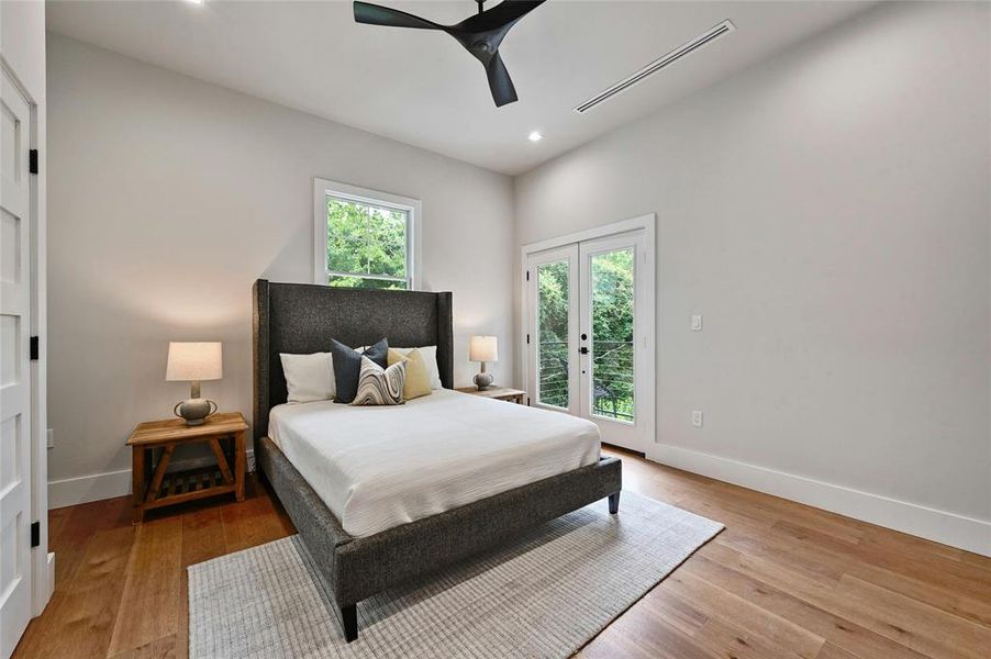 The primary bedroom on the second floor features an en-suite bath and private balcony. The wood floor adds a warm and inviting ambiance to the space, creating a harmonious blend of comfort and elegance.