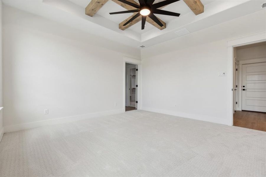 Empty room featuring beam ceiling, ceiling fan, and carpet